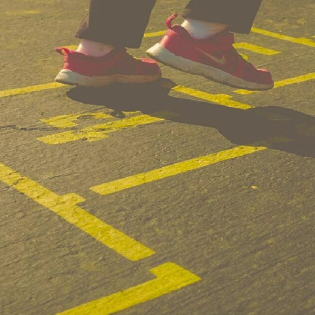 Person jumping on yellow hopscotch grid